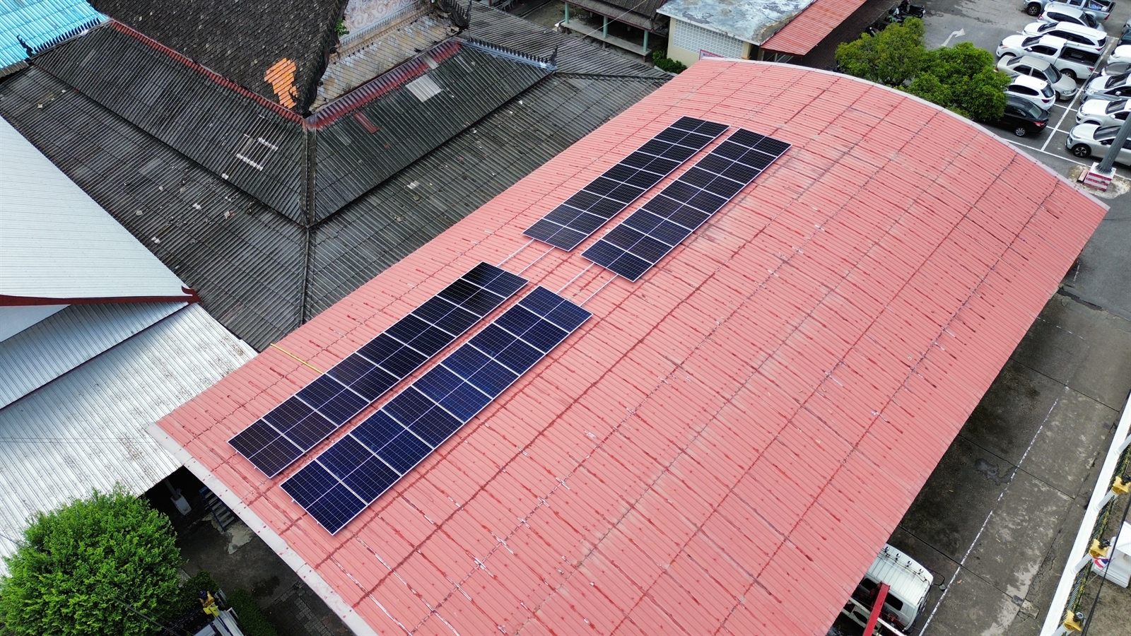 แผงโซล่าเซลล์ระบบไฮบริด 20 kW บนหลังคาเมทัลชีทโค้งของศาลาวัดขจรรังสรรค์ เมืองภูเก็ต ภาพมุมสูง